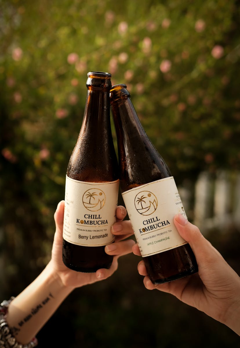 Two people toasting with Chill Kombucha bottles, enjoying a refreshing moment outdoors in Dallas.