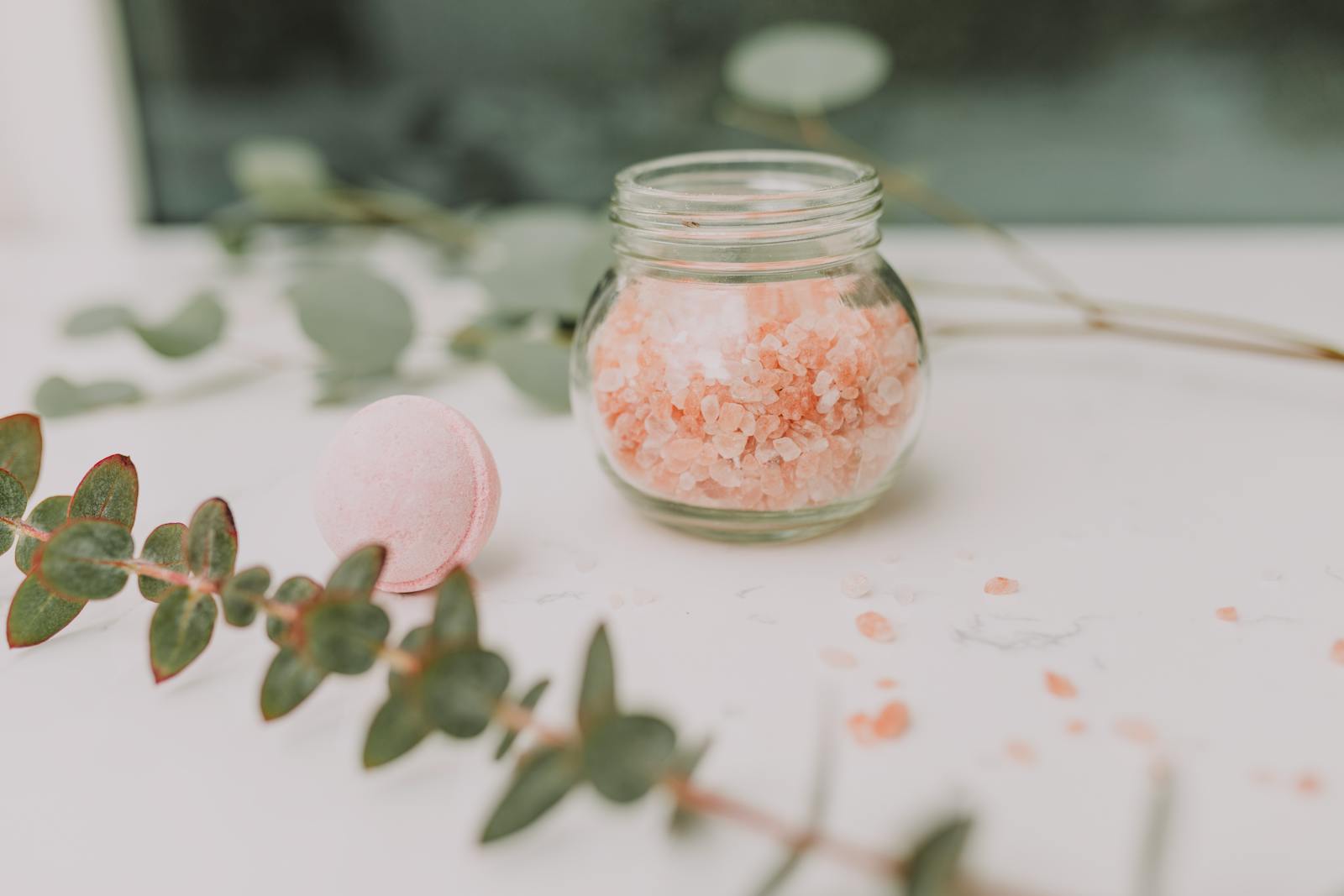 Calming spa scene featuring pink bath salt and eucalyptus for a relaxing experience.
