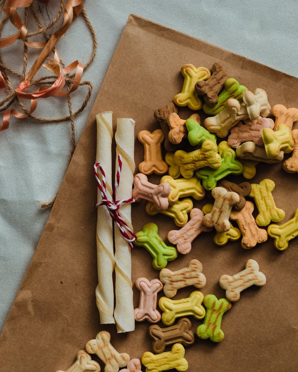 A vibrant assortment of bone-shaped dog treats displayed on brown paper, perfect for pets.