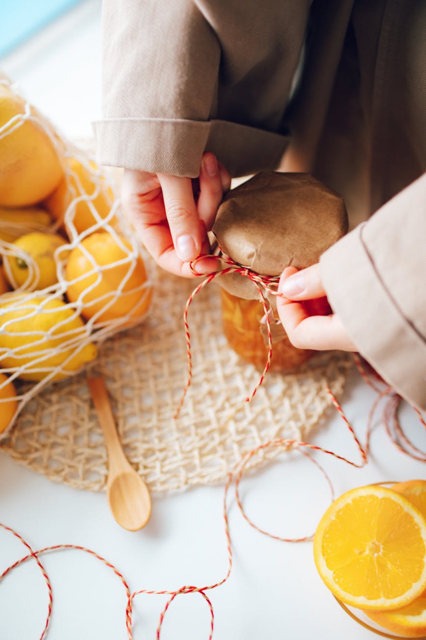 person decorating jars of homemade orange jam